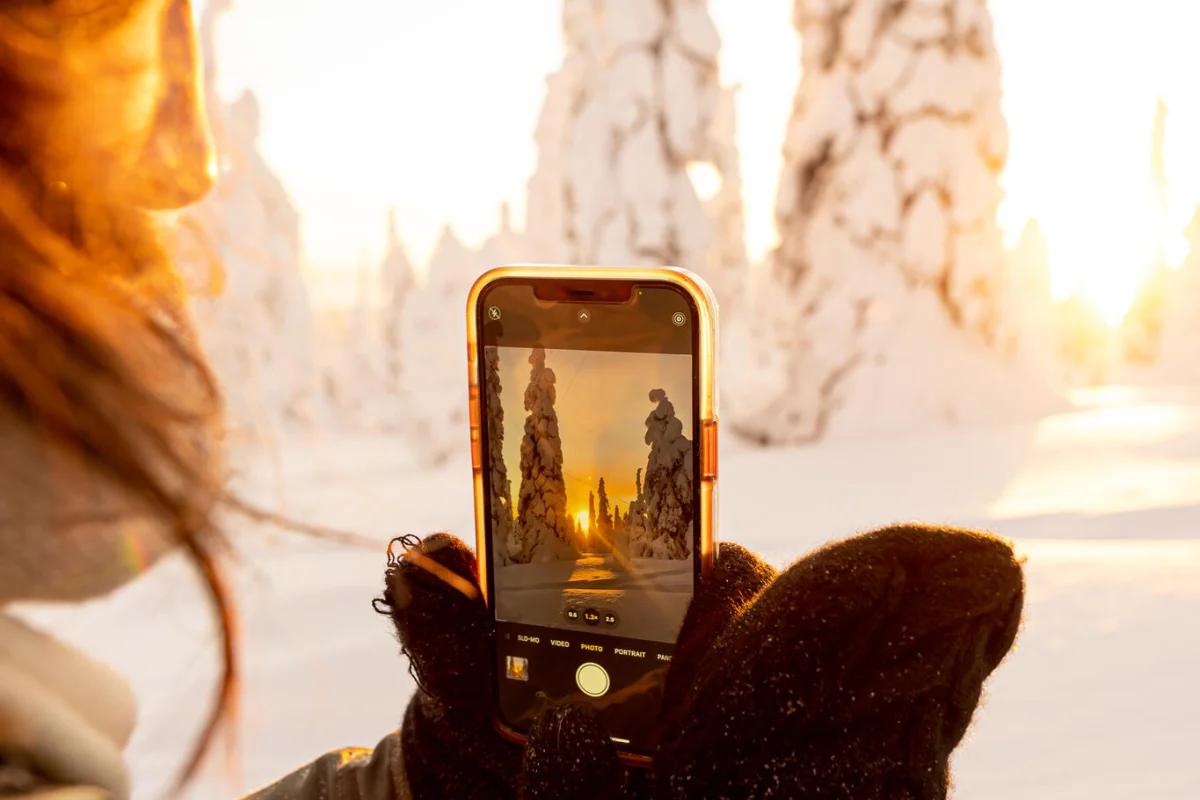 Traveller photographing snow-covered trees with a phone