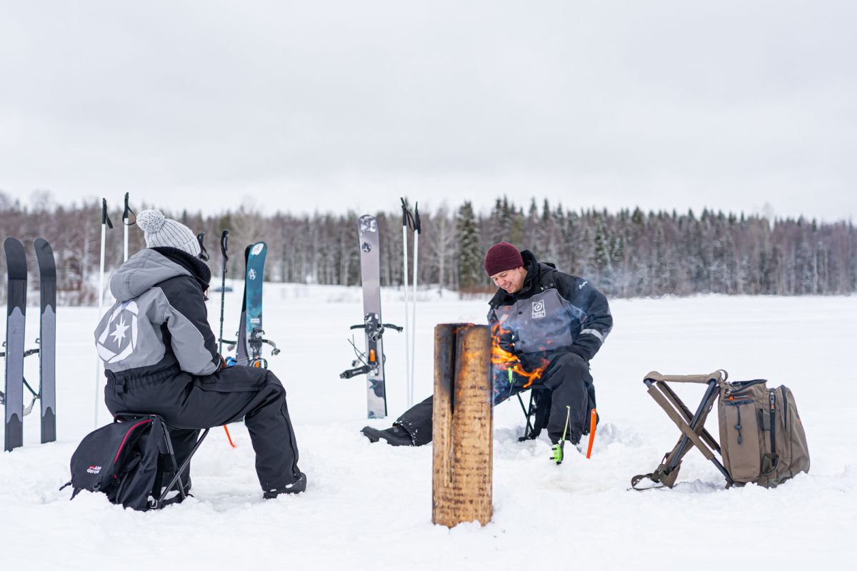 Guest ice fishing on a frozen lake in Lapland