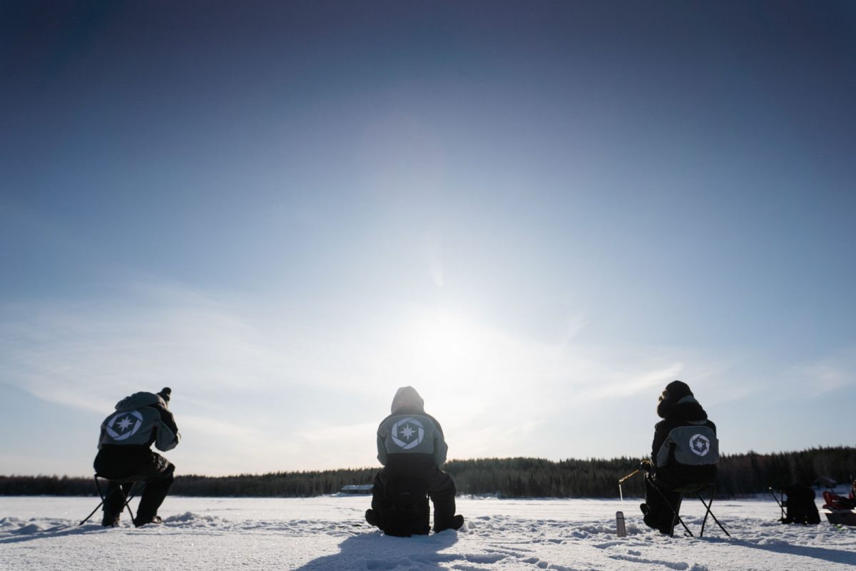Ice fishing on a sunny winter day in Lapland