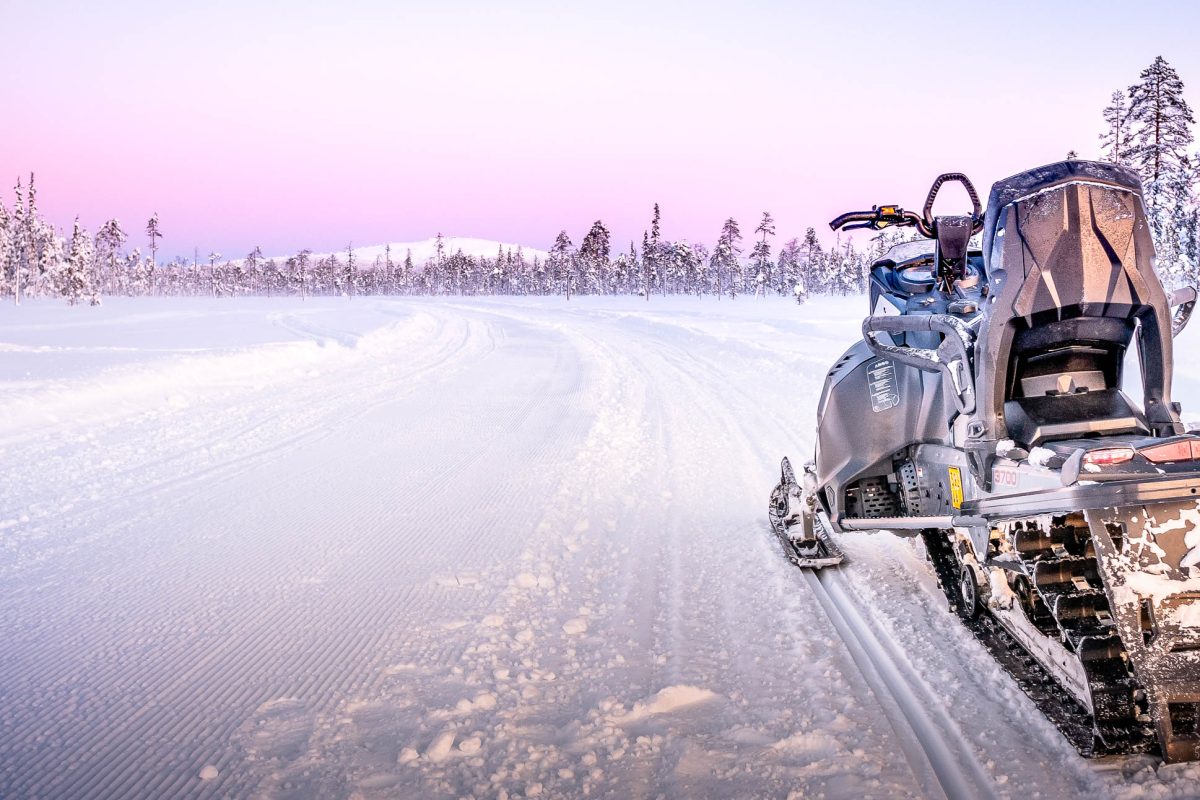 Snowmobiling through a forest at sunset in Levi